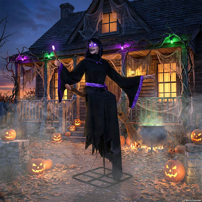 Bruja flotante en escoba frente a una casa decorada para Halloween