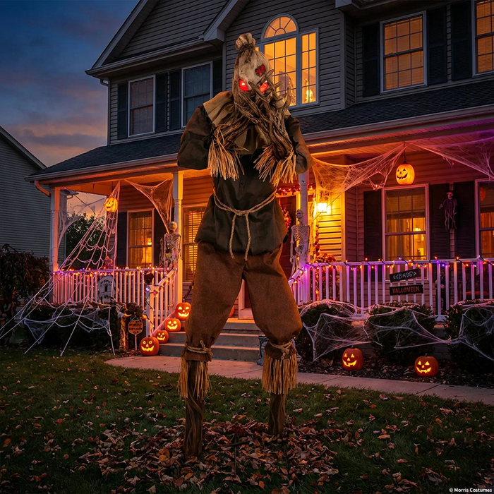 Espantapájaros con ojos rojos frente a una casa decorada para Halloween