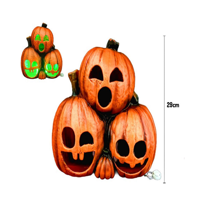 Tres calabazas naranjas apiladas con caras talladas y luz LED