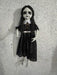 Muñeca gris colgante animada con vestido negro y cuello blanco
