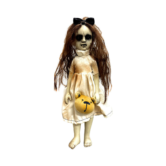 Muñeca de terror con pelo largo castaño, vestido claro, moño negro y osito amarillo