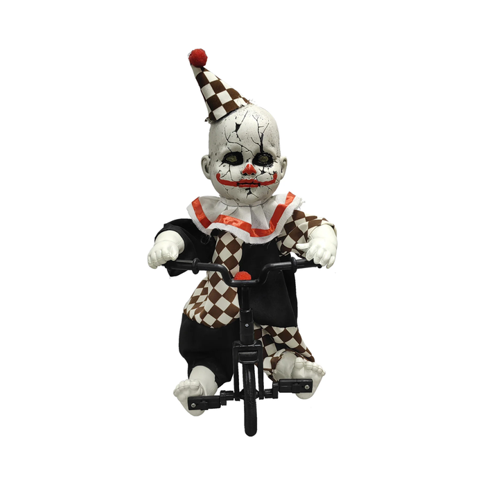 Muñeco payaso animatrónico con cara agrietada, gorro y traje a cuadros café, sentado en un triciclo negro