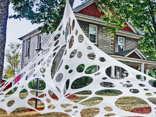 Telaraña gigante elástica blanca estirada frente a una casa, decoración de Halloween